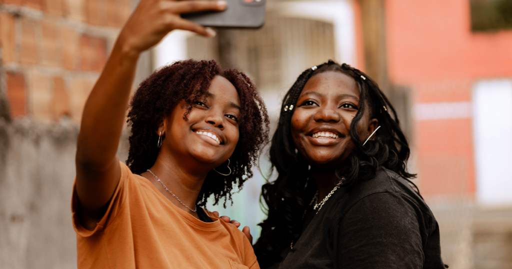 Two African American teens smiling and taking a selfie.