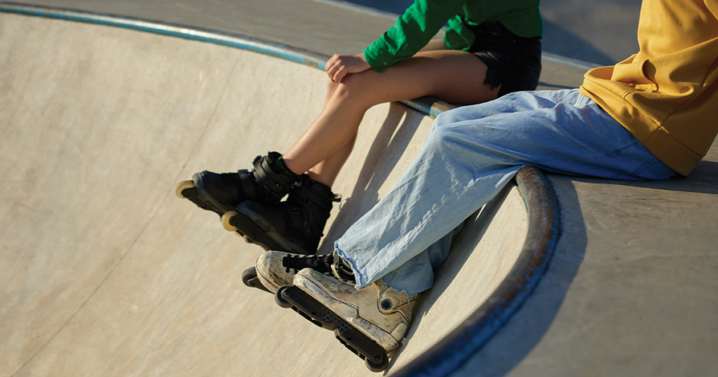 Kids legs with rollerblades at a skatepark.